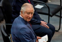 Man in suit holding paper seated and smiling