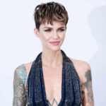 A fashion model with short hair and tattoos posing elegantly