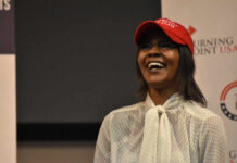 A woman wearing a red cap smiling and speaking at an event