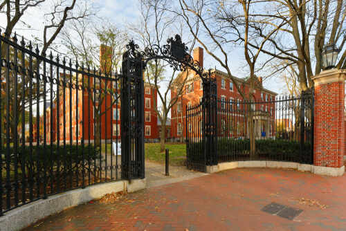 Iron gate opening to a historic university campus with red brick buildings