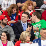 A diverse group of people at a political rally, some engaged in conversation