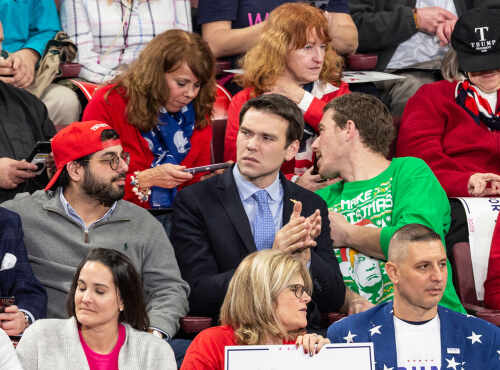 A diverse group of people at a political rally, some engaged in conversation