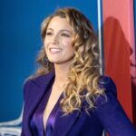 A smiling woman in a purple outfit posing at an event