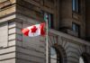 Canadian flag waving in front of a stone building