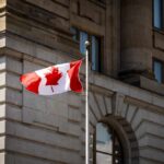 Canadian flag waving in front of a stone building