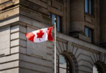 Canadian flag waving in front of a stone building