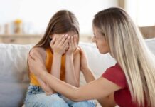 Raising Rebels: The Surprising New Parenting Trend A mother comforting her distressed daughter who is covering her face