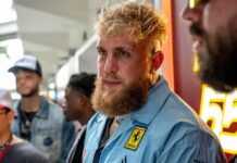 A man with a beard and stylish outfit at an event surrounded by others