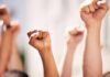 Multiple raised fists in a show of solidarity during a protest