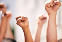 Multiple raised fists in a show of solidarity during a protest