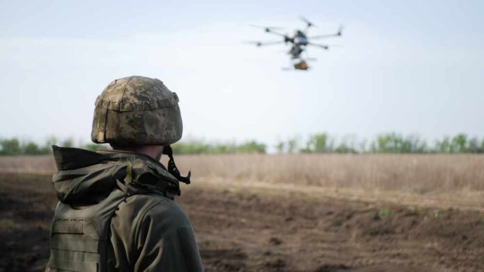 shutterstock_2536116615.jpg A soldier observing a drone flying over a field