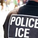 Close-up of a police officer's back with a 'POLICE ICE' badge