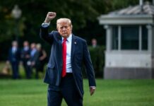 A political figure raising a fist while walking outdoors