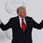 A political figure gesturing with hands during a public appearance