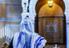 A person wearing a tallit in a synagogue during prayer