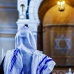 Tehran Synagogue Destruction—What’s the Real Impact? A person wearing a tallit in a synagogue during prayer