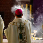 Clergy in ornate vestments during a church service with incense smoke