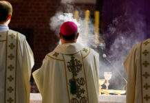 Clergy in ornate vestments during a church service with incense smoke