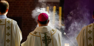 Clergy in ornate vestments during a church service with incense smoke