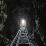 Dark tunnel leading to bright exit with tracks