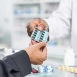 pharmacist handing blister pack of capsules to customer