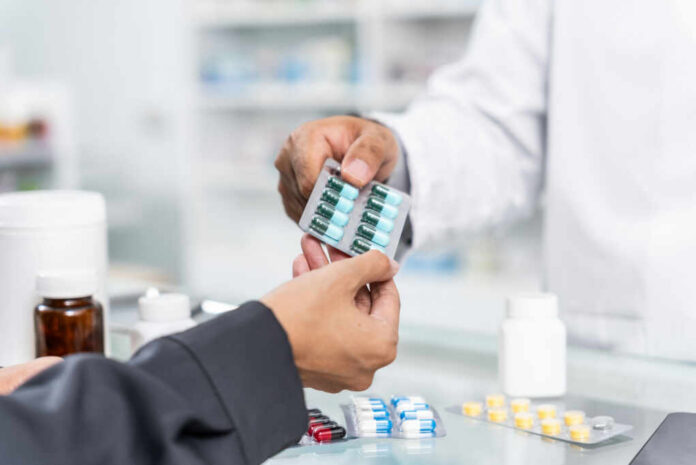 pharmacist handing blister pack of capsules to customer