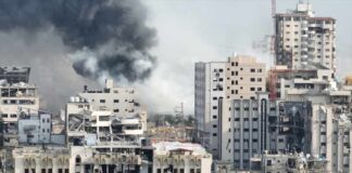 A view of destroyed buildings with smoke rising in the background