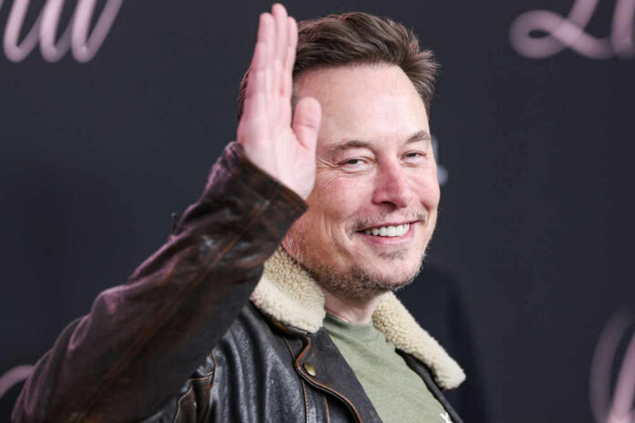 Man smiling while raising his right hand wearing jacket