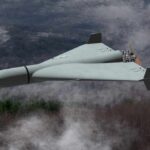 Flying wing drone with pusher propeller over foggy forest