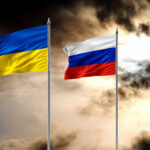 Ukrainian and Russian flags on poles against a dramatic cloudy sky