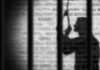 Shadow of a person behind bars on a brick wall