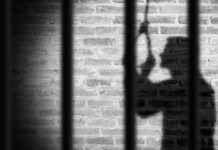 Shadow of a person behind bars on a brick wall