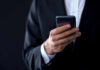 Businessperson in suit holding a smartphone