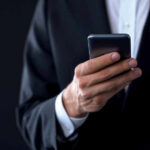 Businessperson in suit holding a smartphone