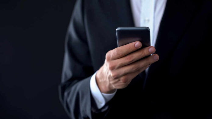 Businessman,Checking,Meeting,Calendar,Online,,Texting,Message,On,Smartphone Businessperson in suit holding a smartphone