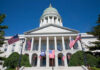 State capitol building with American flags and a green dome