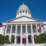 State capitol building with American flags and a green dome