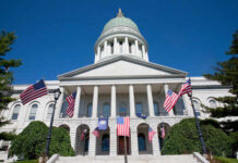State capitol building with American flags and a green dome