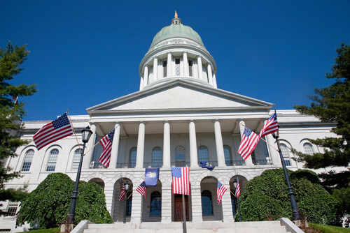 State capitol building with American flags and a green dome