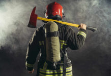 Firefighter holding an axe over their shoulder in a smoky environment