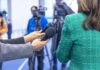 Hands holding microphones in front of a person at a press conference