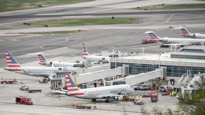 Multiple American Eagle aircraft parked at an airport terminal with ground crew present