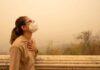 Person wearing a mask in a hazy environment, looking upwards