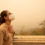 Person wearing a mask in a hazy environment, looking upwards