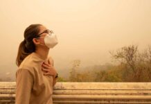 Person wearing a mask in a hazy environment, looking upwards