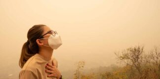 Person wearing a mask in a hazy environment, looking upwards