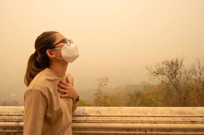 Person wearing a mask in a hazy environment, looking upwards