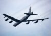 A B-52 bomber flying in the sky with visible jet engines