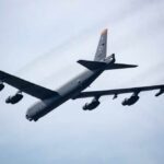 A B-52 bomber flying in the sky with visible jet engines