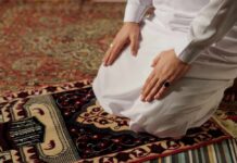 Person kneeling on a prayer rug in traditional attire